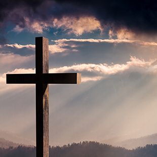 Jesus Christ cross. Christian wooden cross on a background with dramatic lighting, colorful sunset, twilight and orange -  purple clouds and sky.  Easter, resurrection,Good Friday concept